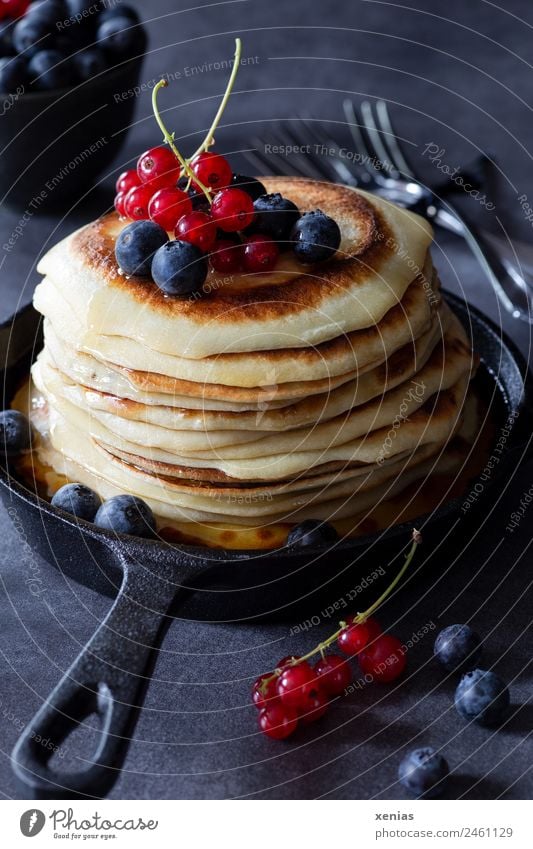 Pancakes with currants and blueberries in a cast iron pan are standing on a dark table Redcurrant fruit Blueberry Cast iron Dough Nutrition Breakfast Buffet