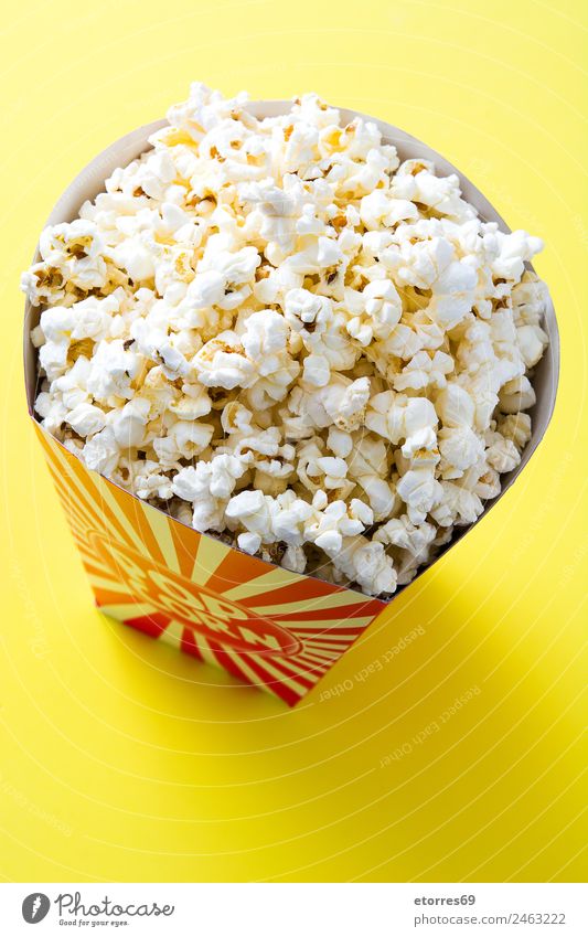 Striped box with popcorn on yellow background. Food Nutrition Eating Finger food Yellow White "popcorn cinema salt butter snack delicious maize isolated striped