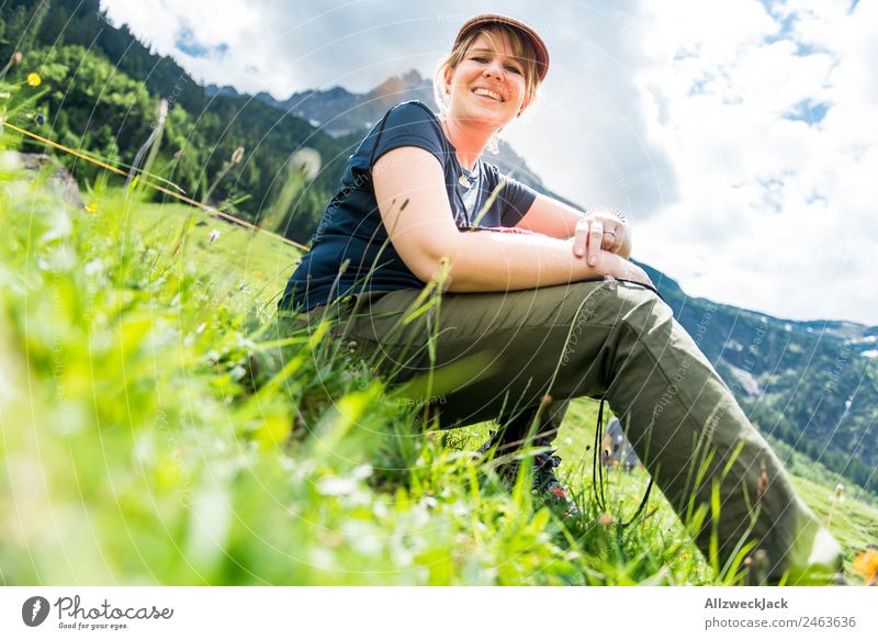 young woman sitting in the grass with mountains in the background Day Beautiful weather Clouds Nature Green Tree Forest Mountain Idyll Vacation & Travel