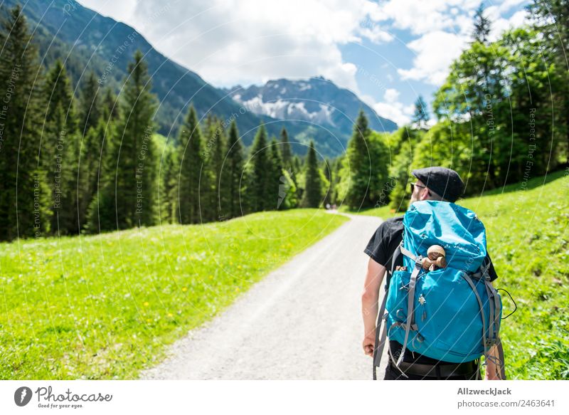 Man with rucksack hiking in the mountains daylight Beautiful weather Clouds cloudy Nature Green trees Forest Idyll vacation Travel photography Hiking