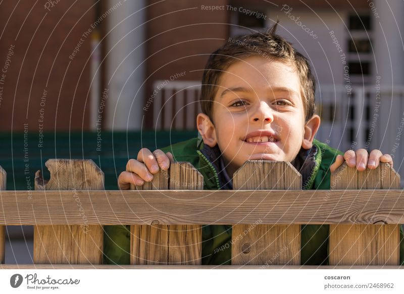 Cute handsome boy look over wooden fence with green coat Joy Face Playing Child Boy (child) Man Adults Infancy Hand Wood Observe Small Curiosity White