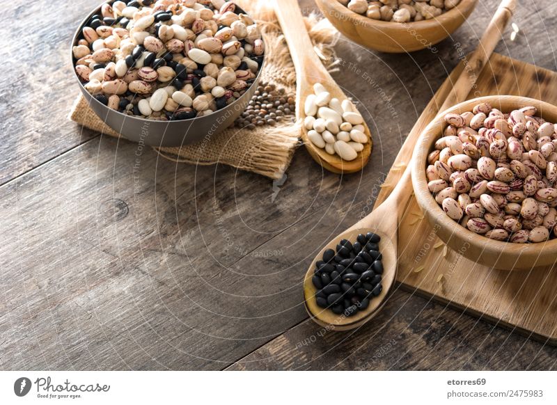 Uncooked assorted legumes in wooden bowl on wood Food Grain Nutrition Eating Organic produce Vegetarian diet Diet Bowl Spoon Nature Brown White Legume Mix Beans
