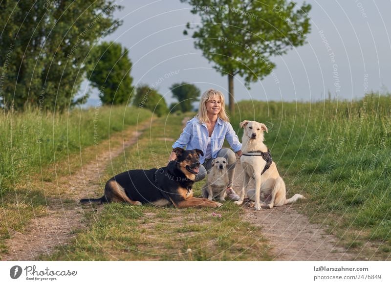 Attractive womanon a rural path with dogs at sunset Lifestyle Summer Woman Adults Friendship 1 Human being 45 - 60 years Nature Landscape Animal Warmth Blonde
