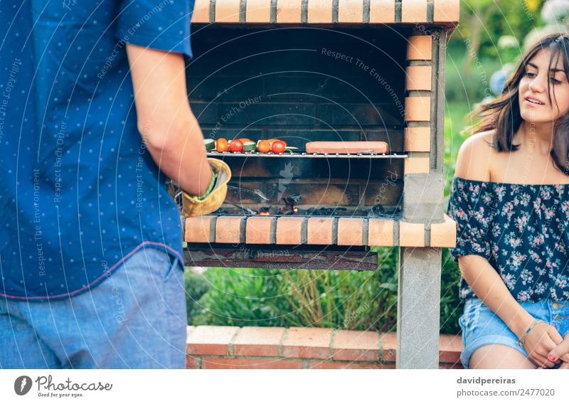 Man cooking sausages and vegetable skewers in a barbecue Sausage Vegetable Lifestyle Joy Happy Relaxation Summer Garden To talk Woman Adults Friendship Hand
