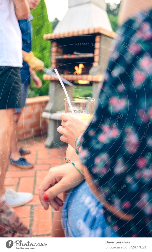 Woman holding lemonade glass and friends cooking in barbecue Sausage Lunch Lemonade Lifestyle Joy Happy Relaxation Leisure and hobbies Summer Garden To talk