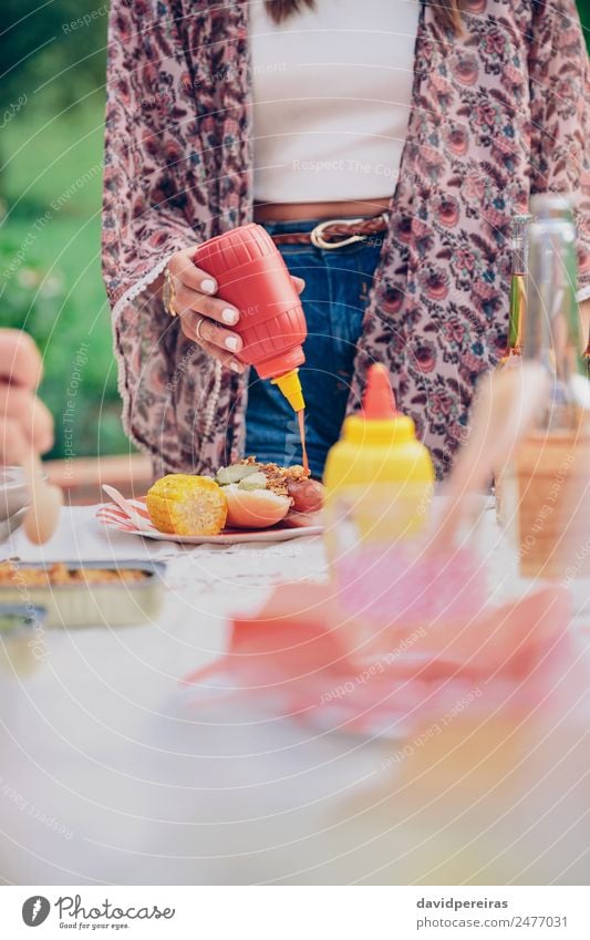 Woman hand pouring ketchup over an american hot dog Meat Sausage Bread Roll Lunch Fast food Beer Plate Bottle Lifestyle Joy Happy Summer Human being Adults