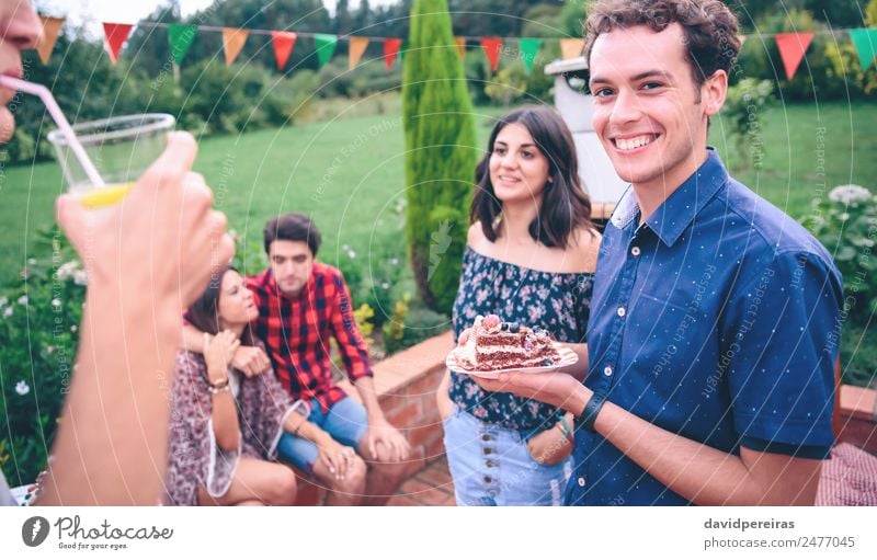 Portrait of young man with a piece of cake in the hands having fun in barbecue with friends Lunch Lemonade Plate Lifestyle Joy Happy Leisure and hobbies Summer