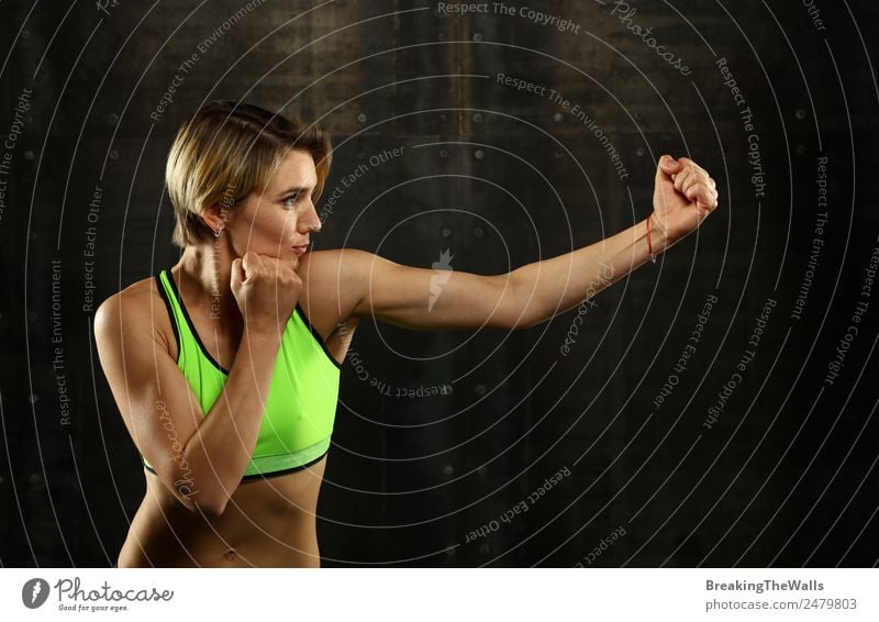 Close up side view profile portrait of one young athletic woman shadow boxing in sportswear in gym over dark background, looking away Lifestyle Sports Fitness