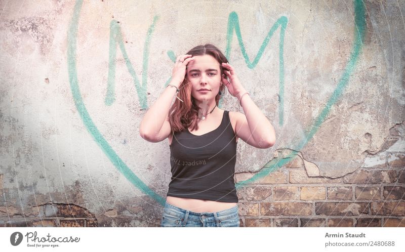 Portrait of a young woman in front of a graffiti heart on a wall Lifestyle Style Design Joy Happy pretty Harmonious Well-being Contentment Senses Relaxation