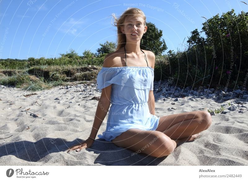 Young woman sitting cross-legged on the beach in a short summer