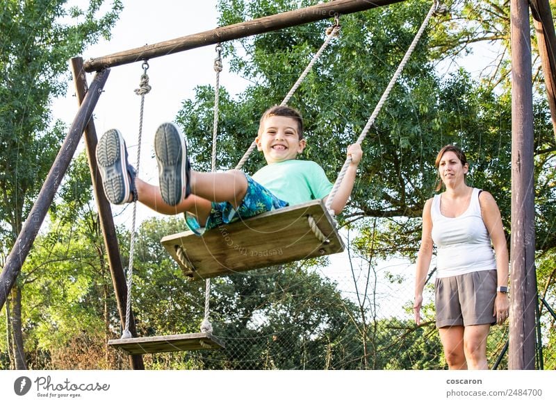 Mother swinging her son on a sw