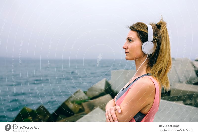 Sportswoman with headphones watching the sea Lifestyle Wellness Relaxation Calm Ocean Music Human being Woman Adults Fog Concrete Observe Think Fitness