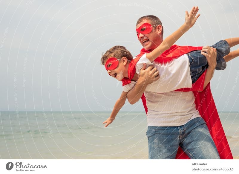 Father and son playing superhero on the beach at the day time. People having fun outdoors. Concept of summer vacation and friendly family. Lifestyle Joy Happy
