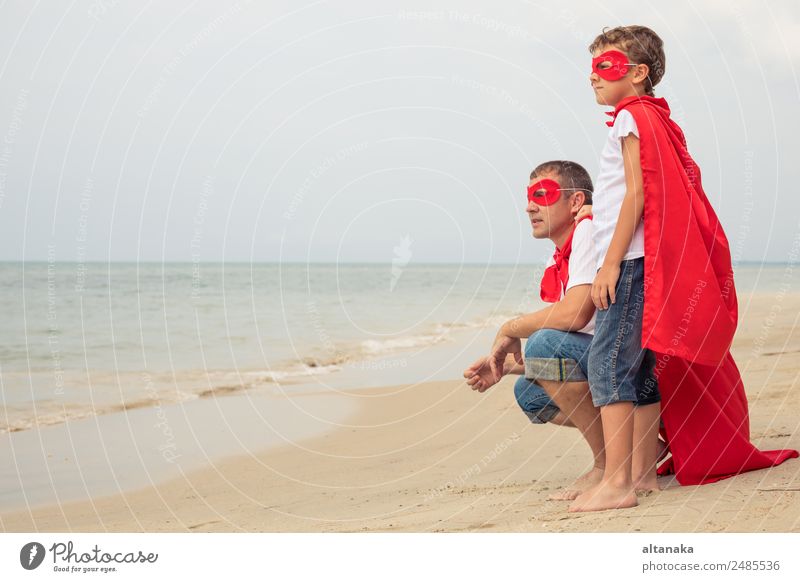 Father and son playing superhero on the beach at the day time. People having fun outdoors. Concept of summer vacation and friendly family. Lifestyle Joy Happy