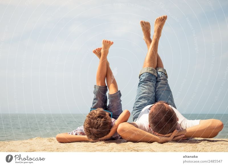Father and son playing on the beach at the day time. People having fun outdoors. Concept of summer vacation and friendly family. Lifestyle Joy Happy Relaxation