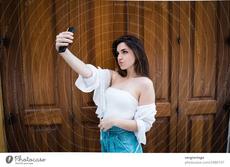 Trendy woman taking selfie at wooden door Elegant Style Beautiful Calm Leisure and hobbies Summer PDA Technology Woman Adults Clothing Brunette Wood Stand