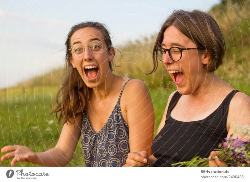 Two women sitting in a meadow laughing. Lifestyle Joy Happy Human being Feminine Brothers and sisters Sister Family & Relations Youth (Young adults) 2