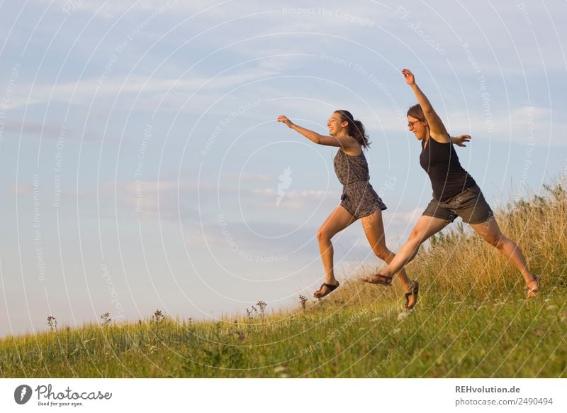2 young women jump across the meadow Lifestyle Leisure and hobbies Human being Feminine Young woman Youth (Young adults) Brothers and sisters Sister Friendship