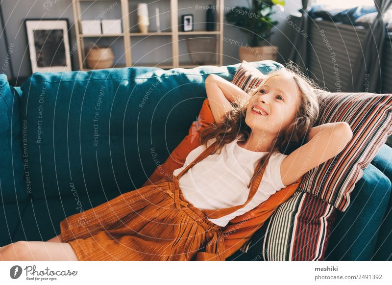 happy kid girl relaxing on cozy couch in modern living room. Lifestyle Happy Flat (apartment) House (Residential Structure) Moving (to change residence)