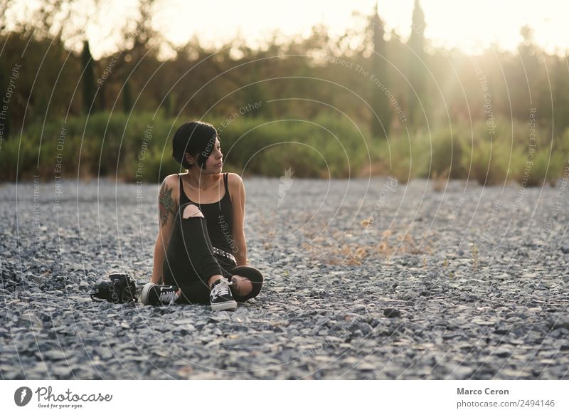 Beautiful photographer girl wearing black clothes sitting on stone floor in countryside with her camera attractive background backlight beautiful breathing