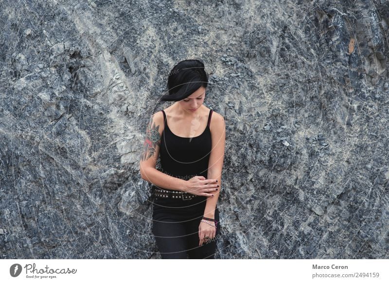 beautiful brunette short hair girl leaning against  gray rock wall outdoors, wearing black clothes attractive background black hair breathing caucasian day
