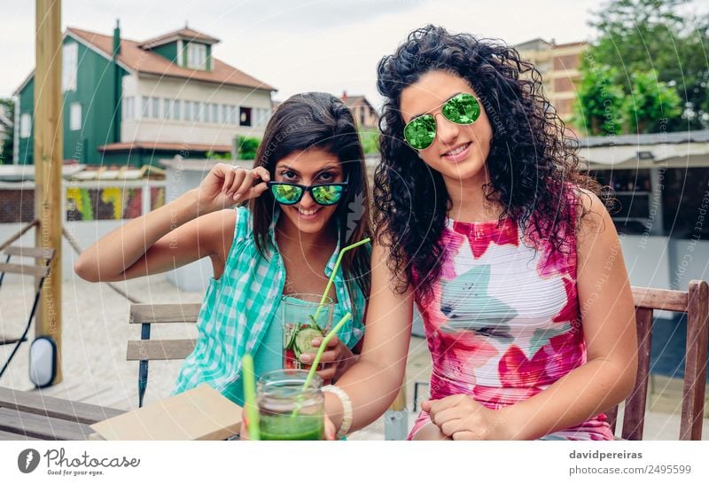 Two women with sunglasses and beverages looking at camera Vegetable Fruit Beverage Juice Lifestyle Joy Happy Leisure and hobbies Summer Human being Woman Adults