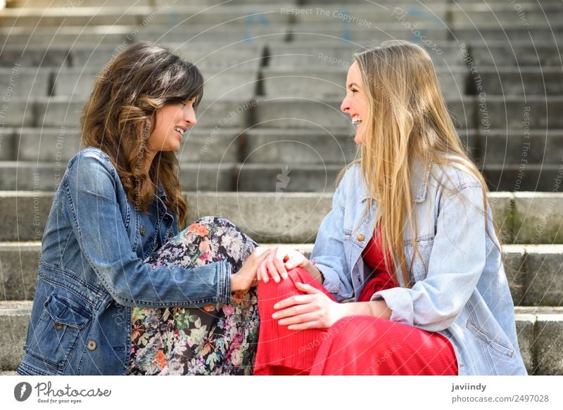 Two young women talking and laughing on urban steps. Lifestyle Style Joy Happy Beautiful To talk Human being Feminine Young woman Youth (Young adults) Woman