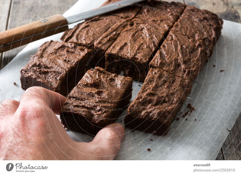 Hand catching a chocolate brownie portion Food Dessert Candy Chocolate Nutrition Organic produce Vegetarian diet Diet Knives Wood Black Cake Home-made Sweet