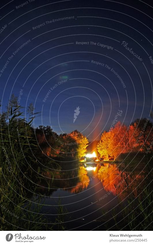 "Above drives the big car". The October fire is reflected in the still waters of a lake in the foreground. The Big Dipper can be seen in the sky.