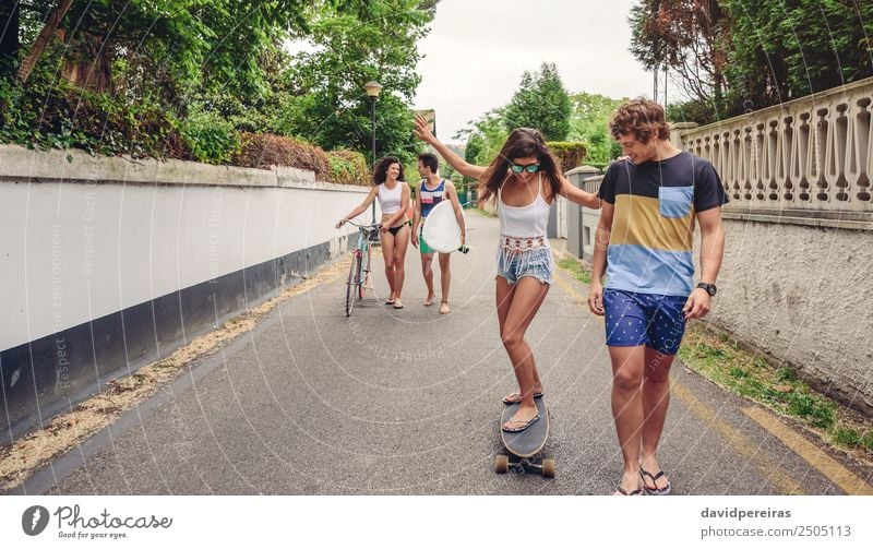 Happy young woman riding on skate with her friends Lifestyle Joy Leisure and hobbies Vacation & Travel Summer Sports Woman Adults Man Friendship Couple