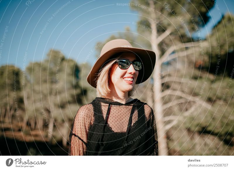 Cute blonde girl with sunglasses and a hat having fun in nature with a pine tree forest in the background Lifestyle Style Joy Relaxation Vacation & Travel