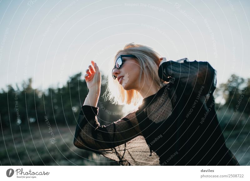 Blonde woman with black dress and sunglasses performing dance in nature with backlight Lifestyle Elegant Style Joy Beautiful Wellness Harmonious Well-being Sun