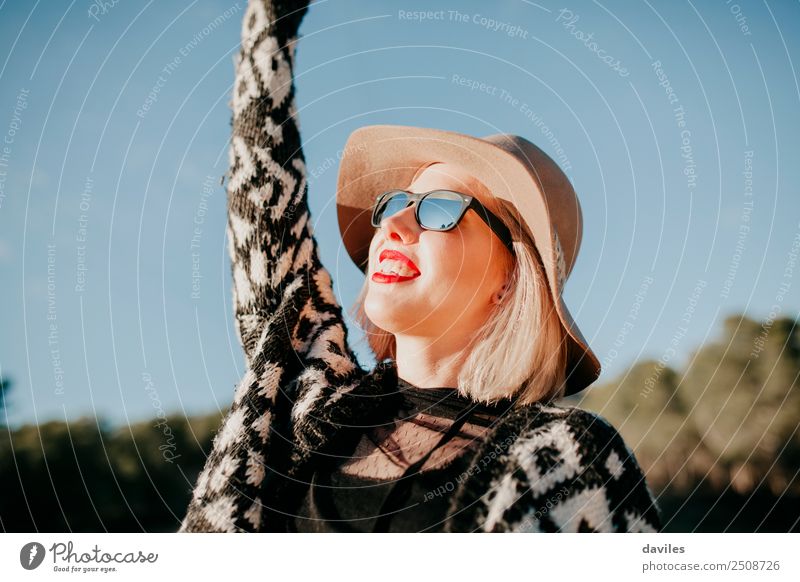 Close up portrait of happy woman with sunglasses and a hat enjoying the sunset in nature and raising the arm. Lifestyle Style Face Wellness Sun Human being