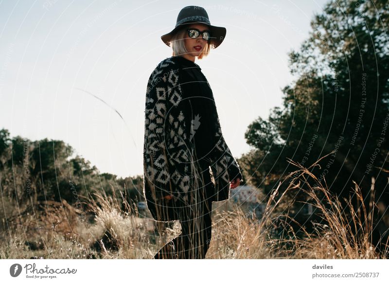 Woman with hat and sunglasses walking in a field at sunset. Lifestyle Luxury Elegant Style Beautiful Leisure and hobbies Vacation & Travel Tourism Trip
