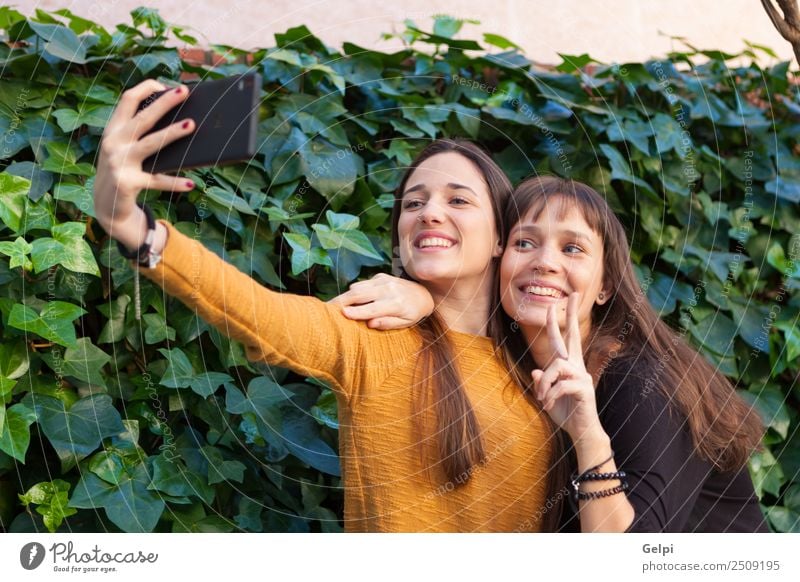 Two sisters enjoying of a day in the park with a mobile Lifestyle Joy Happy Beautiful Playing Telephone Cellphone PDA Technology Internet Woman Adults Sister