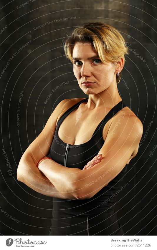 Close up front upper body portrait of one young athletic woman in sportswear in gym over dark background, looking at camera Sports Fitness Sports Training