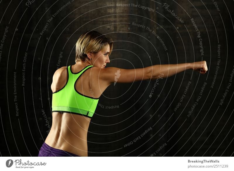 Close up side view profile portrait of one young athletic woman shadow boxing in sportswear in gym over dark background, looking away Lifestyle Sports Fitness