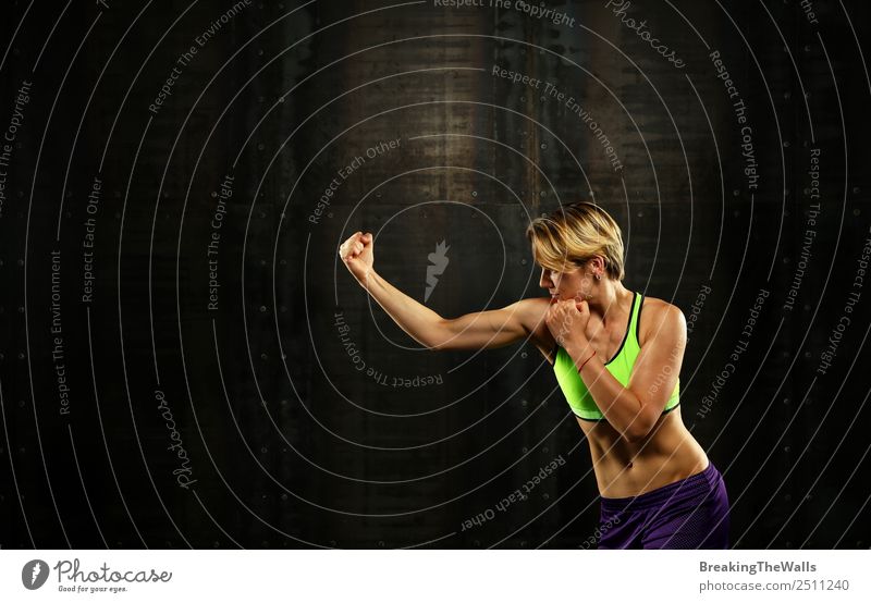 Close up side view profile portrait of one young athletic woman shadow boxing in sportswear in gym over dark background, looking away Sports Fitness