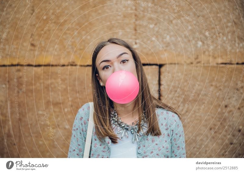 Young girl blowing bubble gum over a stone wall background Lifestyle Joy Happy Beautiful Face Human being Woman Adults Youth (Young adults) Mouth Lips Fashion