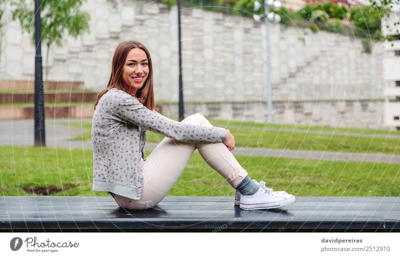 Beautiful young woman sitting on park bench Lifestyle Style Happy Leisure and hobbies Human being Woman Adults Nature Autumn Grass Park Fashion Clothing Jeans