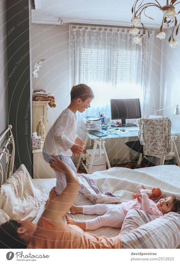 Happy boy jumping and playing over the bed with his family in a relaxed morning. Weekend family leisure time concept. Lifestyle Joy Beautiful Relaxation
