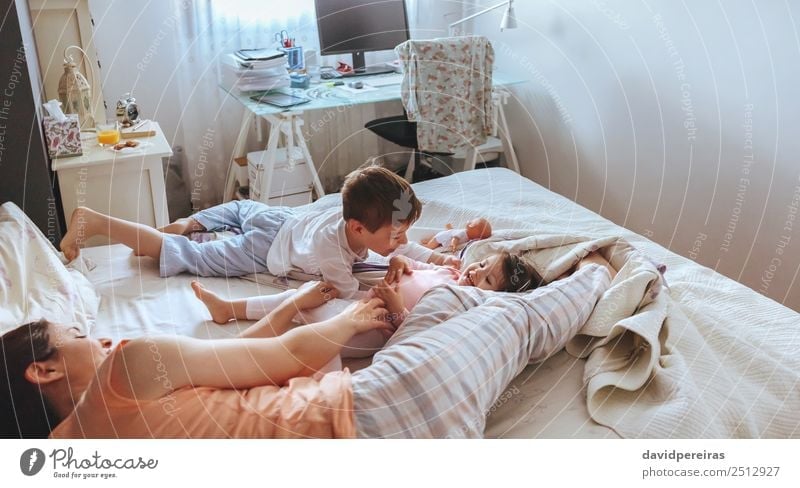 Relaxed mother and sons playing over the bed Lifestyle Joy Happy Beautiful Relaxation Leisure and hobbies Playing Bedroom Child Baby Boy (child) Woman Adults