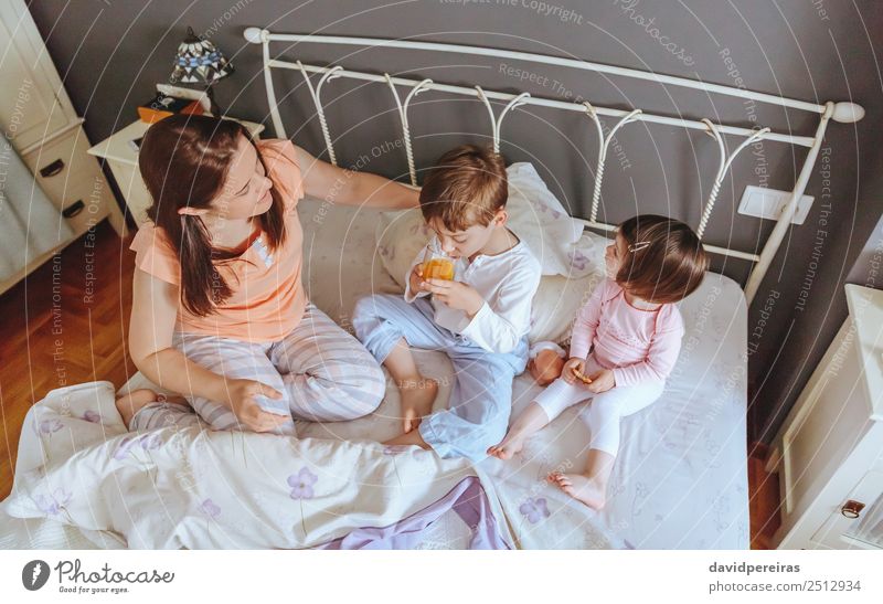 Top view of happy children having breakfast in the bed with their mother in a relaxed morning Eating Breakfast Juice Lifestyle Joy Happy Beautiful Relaxation