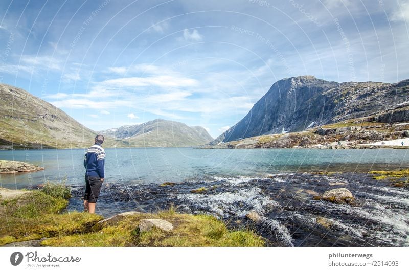 Man stands with feet in the water in the mountain lake Environment Nature Landscape Clouds Summer Beautiful weather Rock Alps Mountain Peak Coast Lakeside Bay