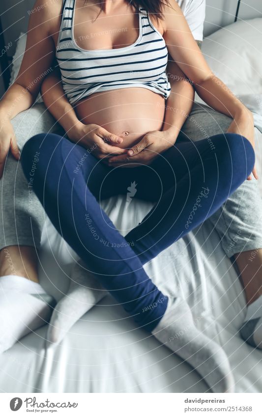 Pregnant woman embraced by her husband Bedroom Human being Baby Woman Adults Man Parents Mother Father Family & Relations Couple Partner Hand Love Sit Embrace