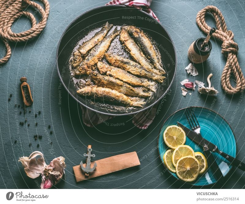 Fried sardines in a pan on the kitchen table with ingredients Food Fish Nutrition Dinner Organic produce Vegetarian diet Crockery Plate Pan Cutlery Style Design