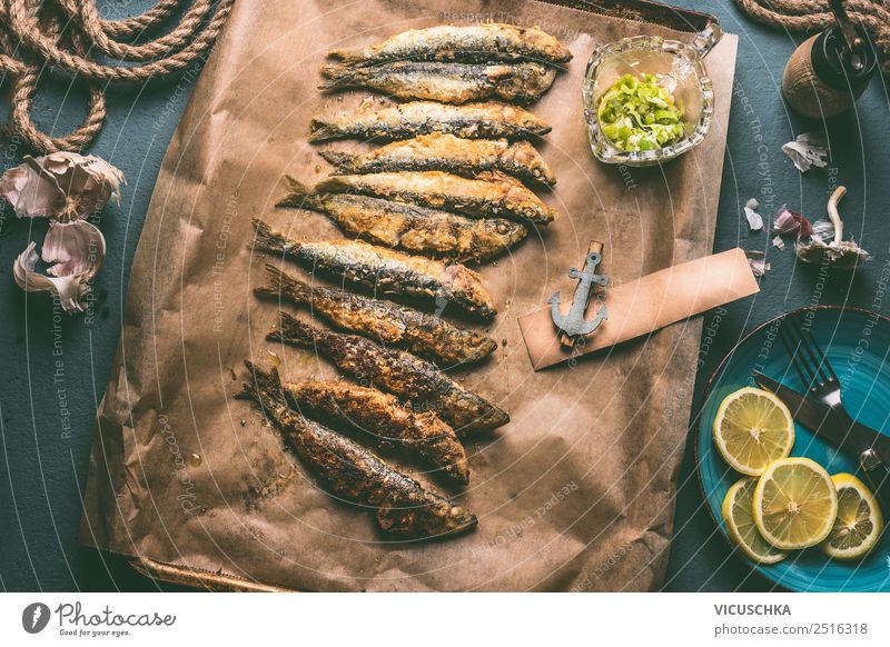 Grilled sardines on baking tray with ingredients: lemon, garlic and herbs for tasty seafood eating. Cooking preparation of fishes grilled cooking fresh small