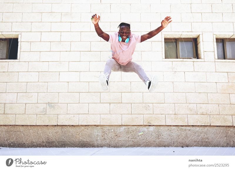 Happy young man jumping in an urban place Lifestyle Style Joy Healthy Athletic Wellness Well-being Leisure and hobbies Freedom Headset Headphones Human being
