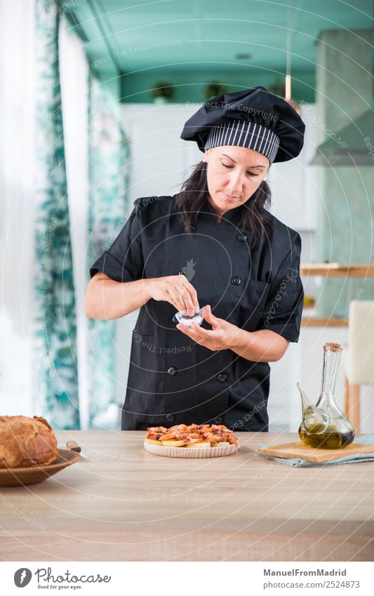 woman chef seasoning a dish Herbs and spices Nutrition Plate Table Kitchen Human being Woman Adults Hand Hat Wood Modern cook adding salt Octopus galician pulpo