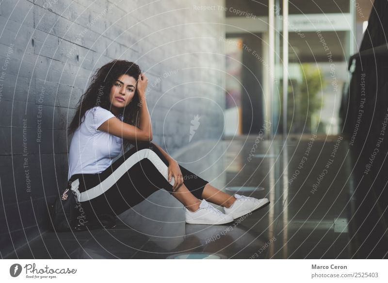 beautiful young woman sitting on the floor in introspective pose. Attractive mixed race girl casual dressed sitting on the street thnking about her dreams.t
